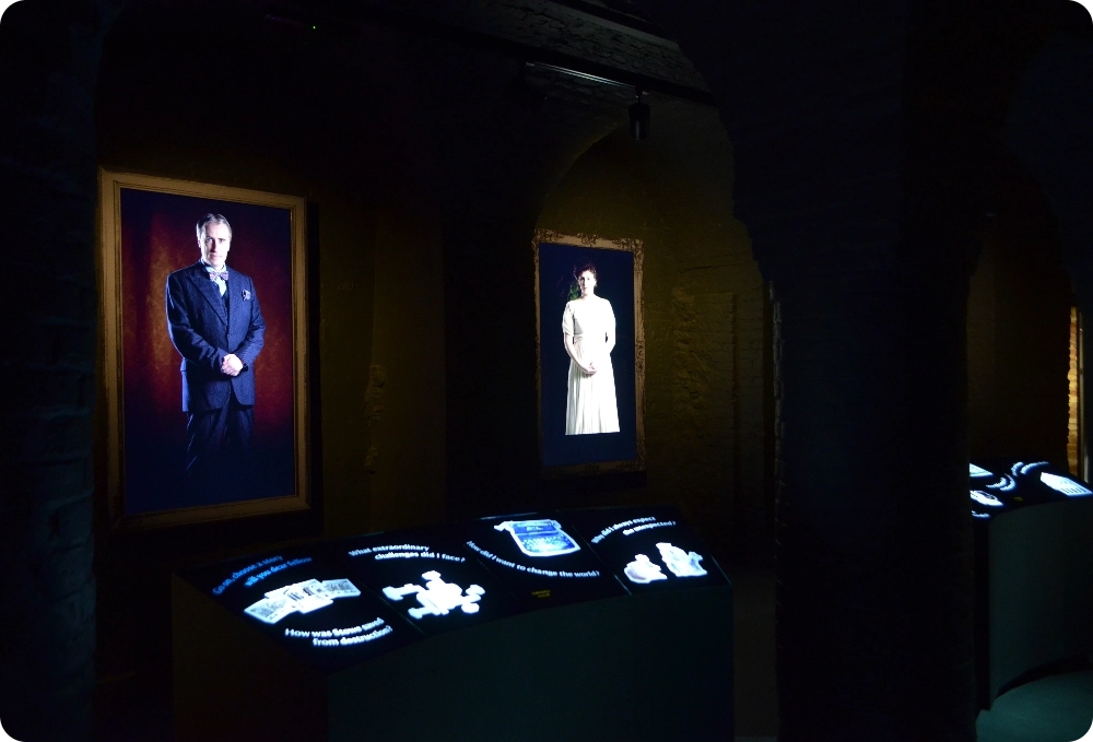 The museum is dark to allow two illuminated screens in the shapes of paintings to display a headteacher and a duchess. These are talking portraits which visitors can interact with via touch panels and hear and see stories about Stowe's history.
